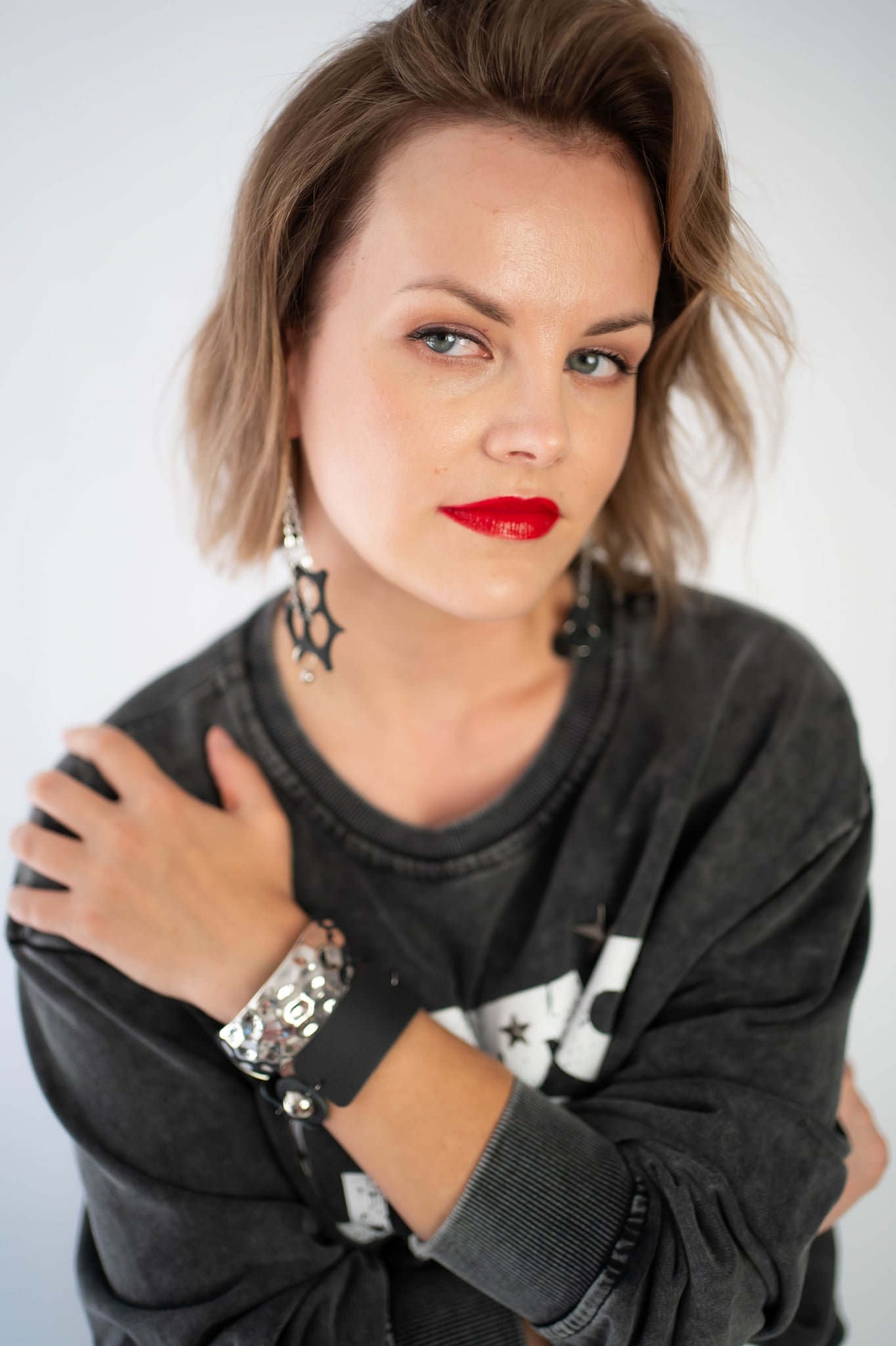 Woman wearing House of Deme zero waste earrings and 4in1 bracelet. Red lips, short bob,  punk/street/rock style wear. 
